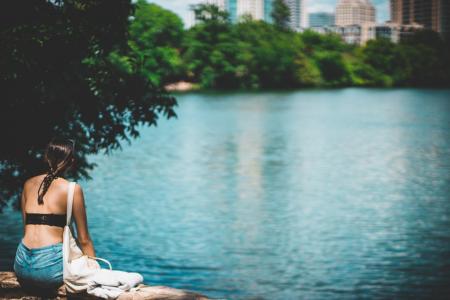 Woman in Black Top Sitting Beside Body of Water