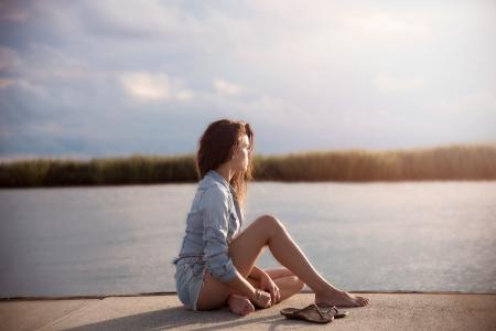 Woman In Blue Denim Jacket Sitting Near Body Of Water