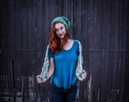 Woman in Blue Scoop-neck Shirt and Green Beanie Cap Standing in Front of Black Wooden Fence