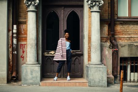 Woman in Blue Strapless Top and Black Pants Standing Next to Brown Wooden Door