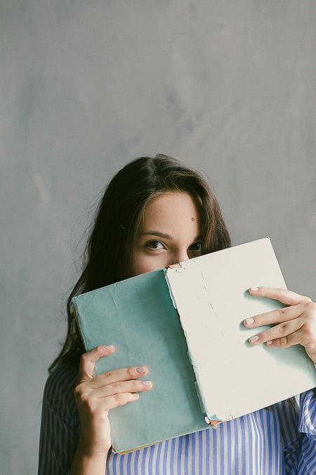 Woman in Blue Striped Flannel Shirt Holding a Book Indoors