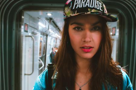 Woman in Blue Top Wearing Black and White Cap With Paradise Text-printed