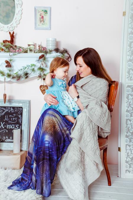 Woman in Blue White and Brown Dress Holding Baby in Teal Dress Inside House