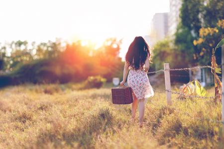 Woman in Brown Floral Dress Walking Near Fence