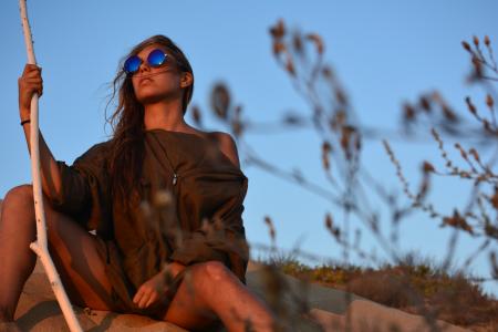 Woman in Brown Shirt Sitting Near Green Plant Under Clear Blue Sky