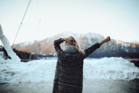 Woman in Gray and Black Tribal Cardigan Standing in Front of Snow Fields