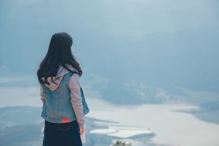 Woman in Gray and Blue Zip-up Hoodie Standing on the Cliff