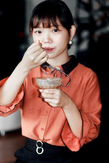 Woman in Orange Dress Holding Brown Liquid Filled Glass Cup