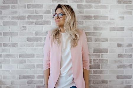 Woman in Pink Cardigan and White Shirt Leaning on the Wall