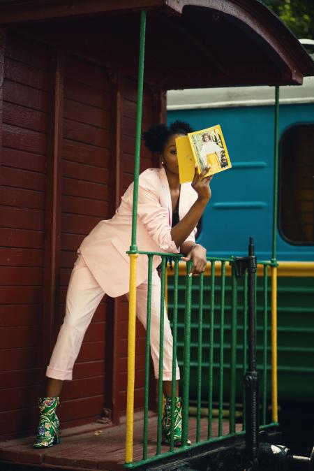 Woman in Pink Suit Coat Leaning on Green Steel Fence