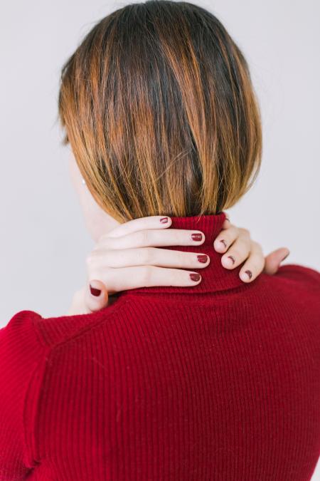 Woman in Red Turtle-neck Shirt Touching Her Neck