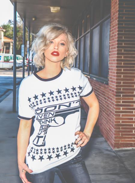 Woman in White and Black Crew-neck T-shirt Stands on Pathway Near Red Bricked Building