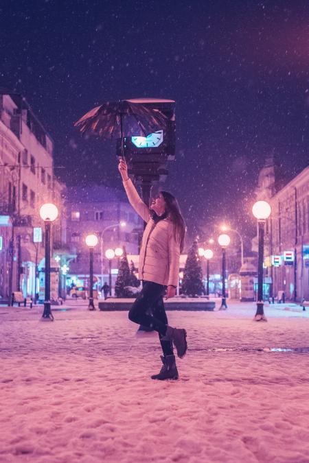 Woman in White Bubble Jacket and Black Jeans Standing While Holding Umbrella