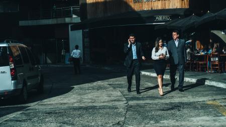 Woman in White Dress Shirt Between Men in Suit Standing on Concrete Ground