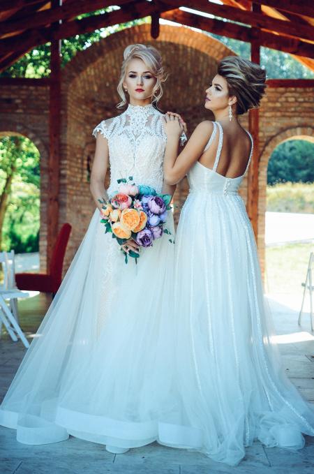 Woman in White Lace Wedding Dress Holding Flower Bouquet Beside Woman in White Dress