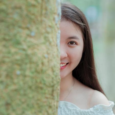 Woman in White Off-shoulder Top Behind Grey Tree Trunk