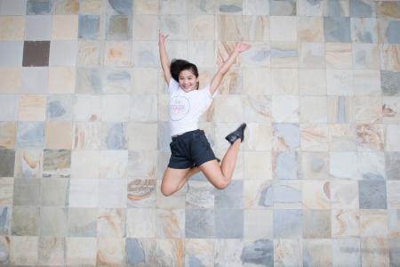 Woman in White Shirt and Black Shorts Taking Jump Shot Near Wall