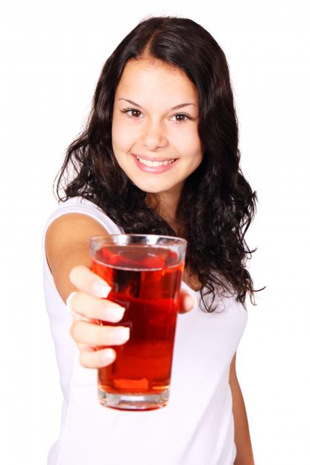 Woman in White Shirt Showing a Filled Drinking Glass