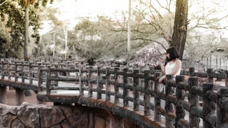 Woman in White Shirt Standing on Black Bridge