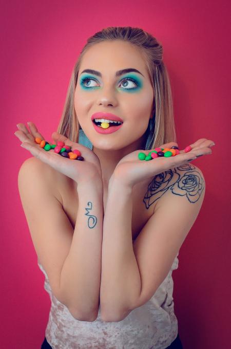 Woman in White Shirt With Candies on Her Hand