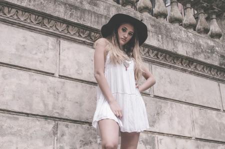 Woman in White Sleeveless Dress and Hat Near Wall