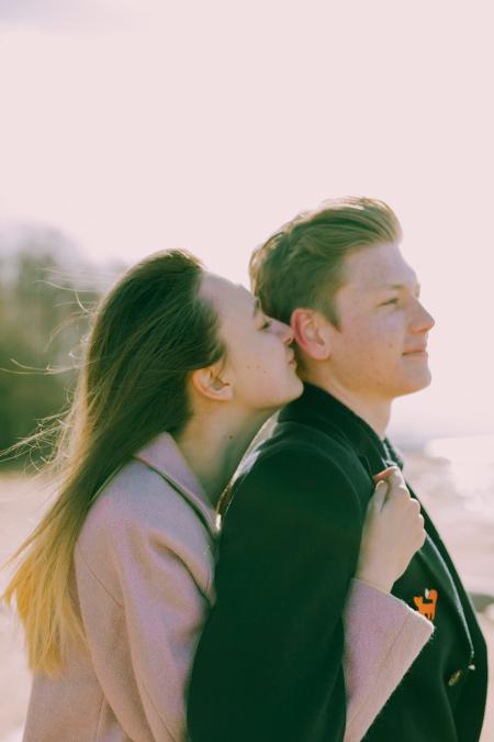 Woman Kissing the Back of Man's Ear Near Sea