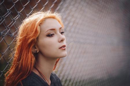 Woman Leaning on Gray Chain Link Fence
