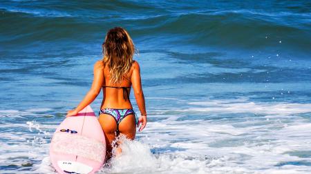 Woman on Large Body of Water during Daytime Holding Surf Board