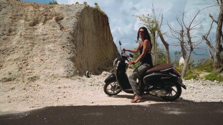 Woman Riding Motor Scooter Travelling on Asphalt Road during Sunrise