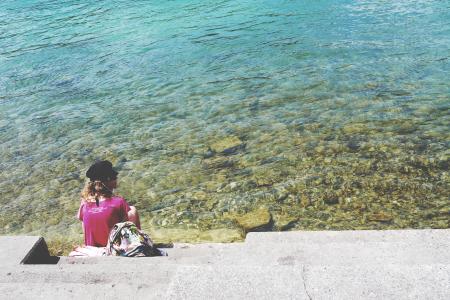 Woman Sitting in Front of Sea during Daytime