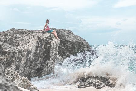 Woman Sitting of Rock Near Body of Water