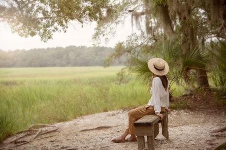 Woman Sitting on Bench Near Forest and Grass