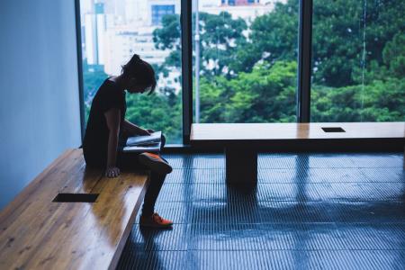 Woman Sitting On Brown Wooden Chair Beside Glass Window