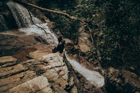 Woman Sitting on Edge Beside Flowing River