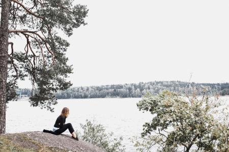 Woman Sitting on Gray Soil Near Body of Water