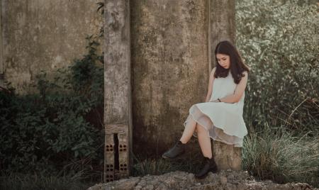 Woman Sitting on Slab Near Brown Wall