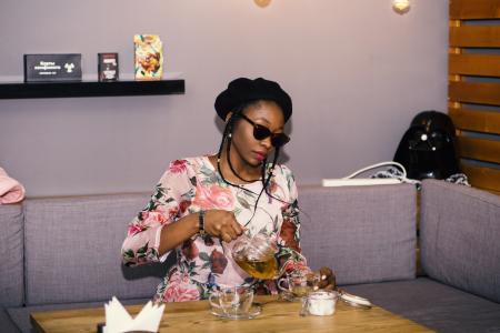 Woman Sitting on Sofa in Front of Table While Holding Clear Glass Teapot