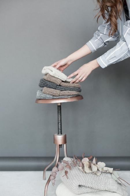 Woman Staking Five Assorted Color Beanies on Brown Steel Stool