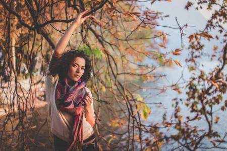 Woman Standing Beside Bare Tree Near Body Of Water