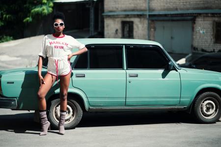 Woman Standing in Front of Teal Sedan