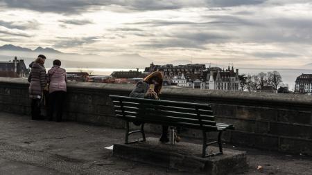 Woman Taking Photo While Sitting on the Bench Behind the Building Scenery