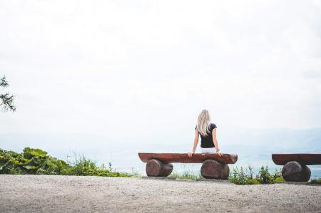 Woman Taking Photo While Sitting on the Bench Behind the Building Scenery