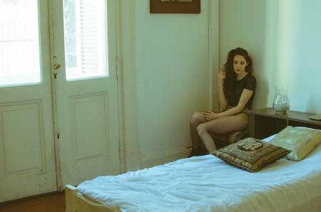 Woman Wearing Black Cap-sleeved Top Sitting on Chair Near Bed
