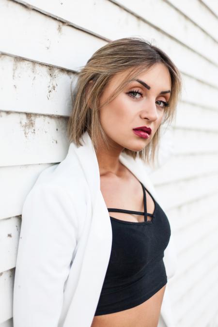 Woman Wearing Black Crop Top Leaning Against White Wall