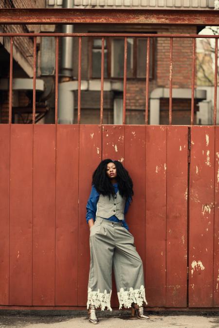 Woman Wearing Blue and Gray Outfit Standing Beside Gate