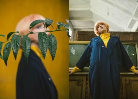 Woman Wearing Blue Coat and Yellow Sweatshirt Leaning on Brown Wooden Storage