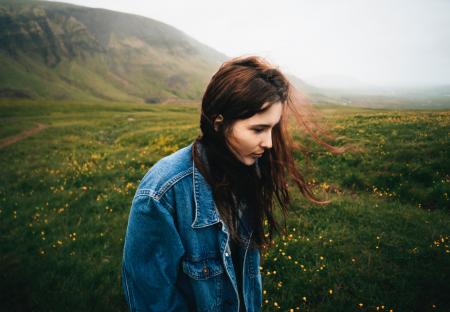 Woman Wearing Blue Denim Jacket Walking on the Green Grass Field