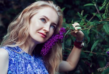 Woman Wearing Blue Floral Sleeveless Dress Smelling Violet Flower