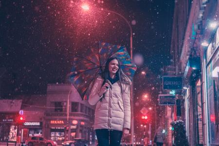 Woman Wearing Brown Bubble Jacket Holding Teal and Yellow Umbrella Near Building