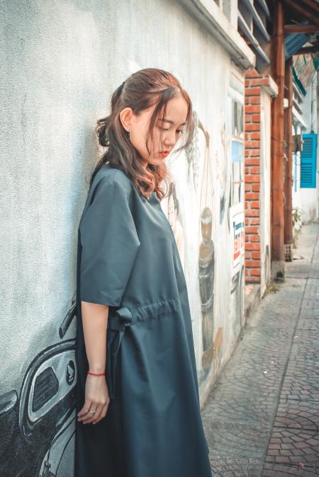 Woman Wearing Gray Coat Leaning on Gray Wall With Graffiti